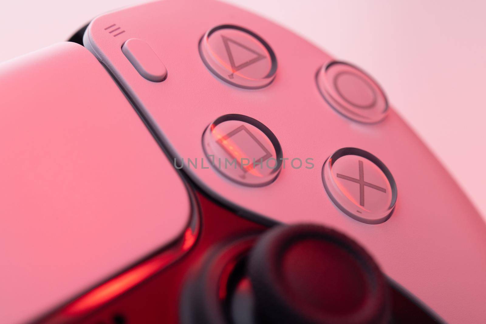 Lviv, Ukraine - February 27 2021: Close up parts of joystick from new Sony PlayStation 5 set-top box. White controller from TV game box in red light by uflypro