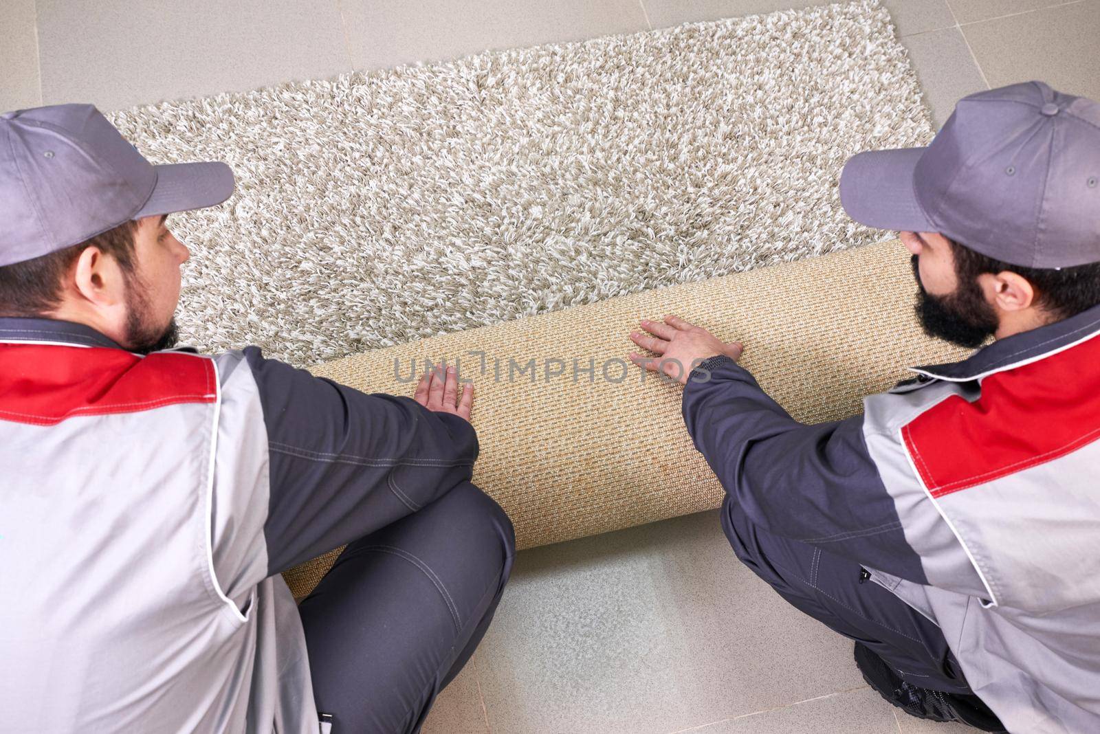 Male Worker Unrolling Carpet On Floor At Home