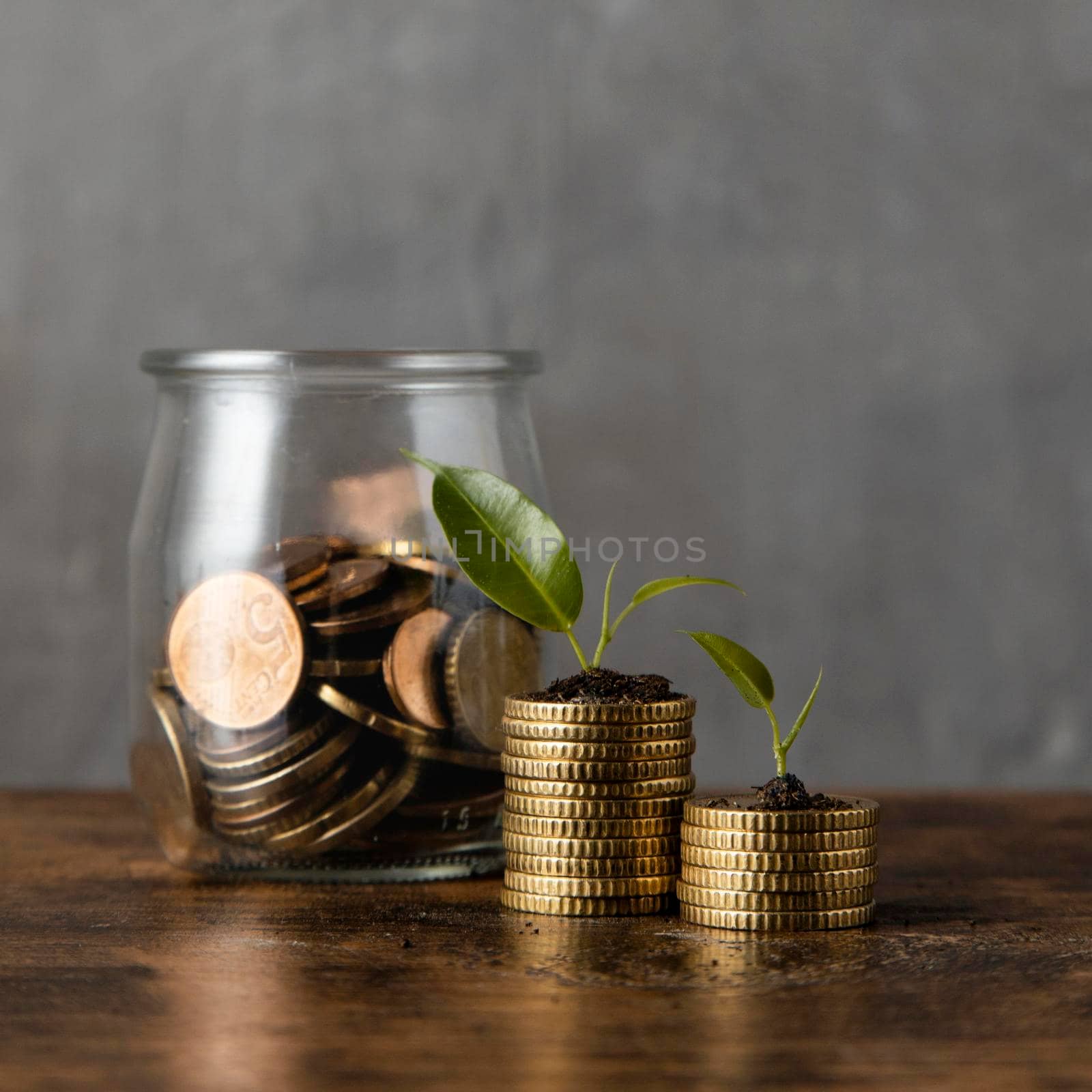 front view two stacks coins with plants jar. High resolution photo