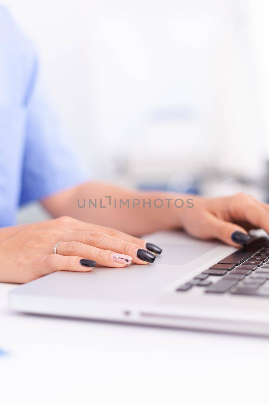Close up of medical specialist typing on laptop in hospital office. Health practitioner searching in hospital database using laptop in hospital cabinet, keyboard, job.