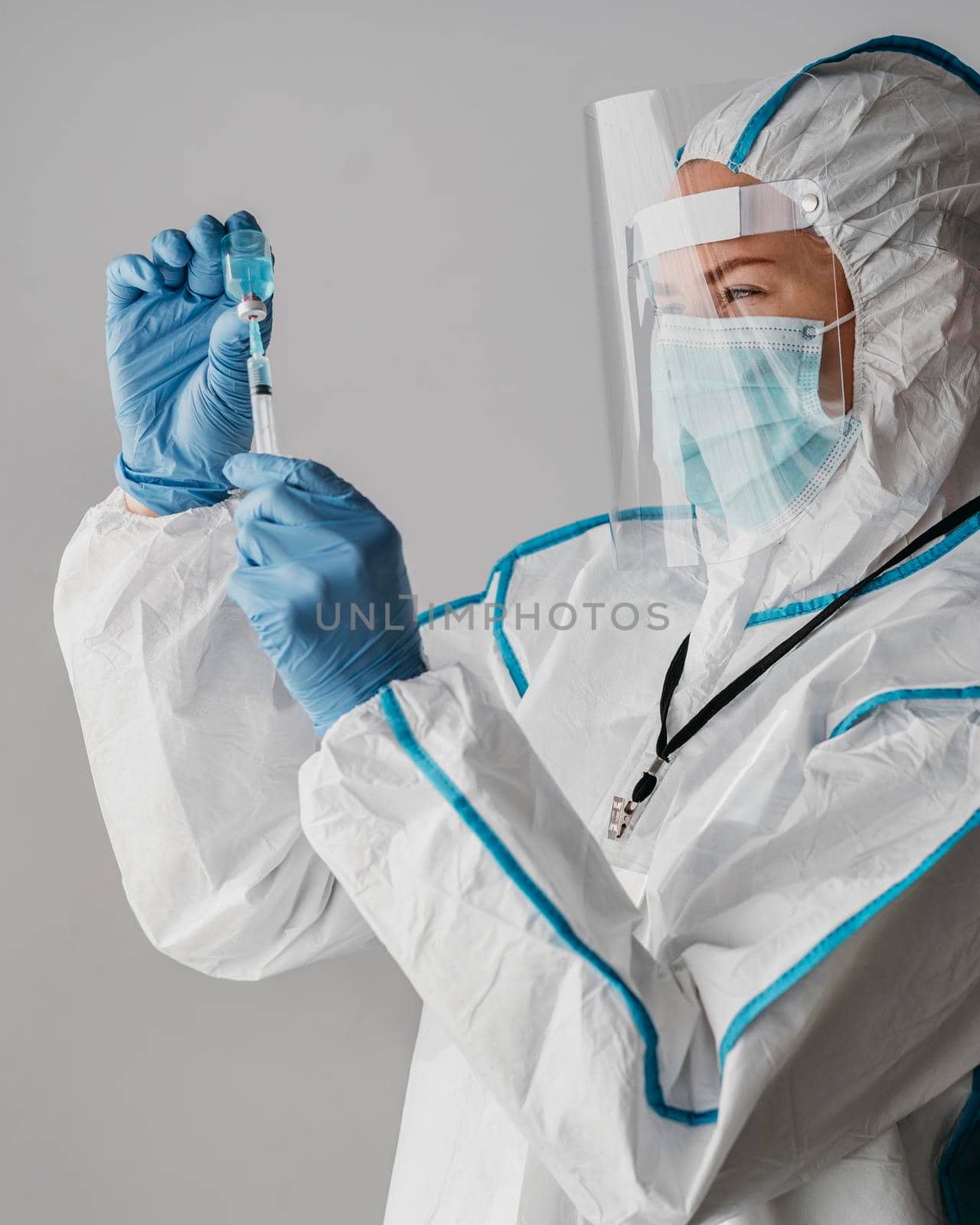 doctor holding vaccine bottle while wearing protective equipment. High resolution photo