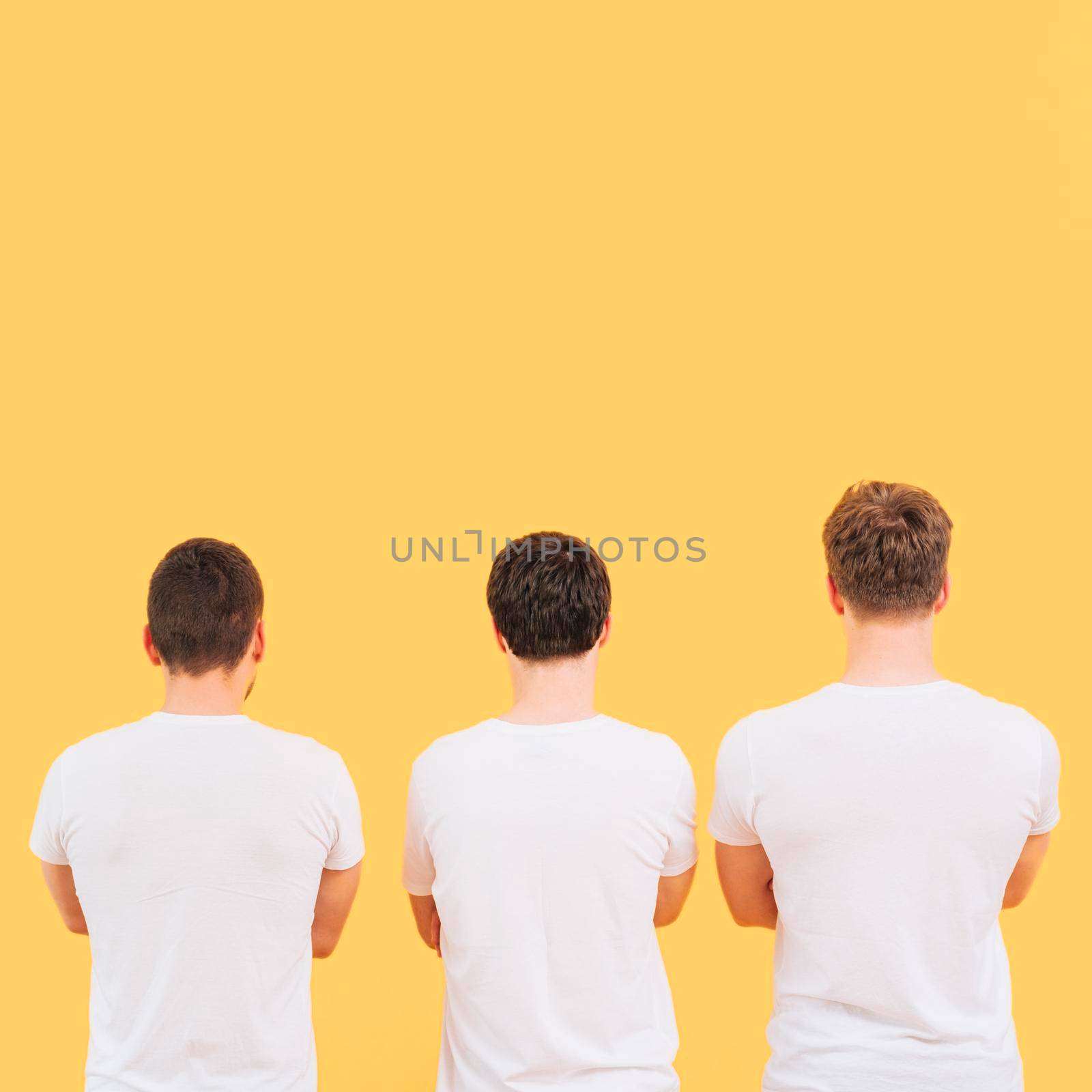 rear view men white t shirt standing against yellow background. High quality photo by Zahard