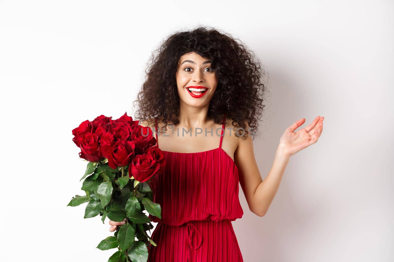 Romance and Valentines day. Woman gasping surprised and happy, receive surprise gift from lover, holding bouquet of red roses, standing on white background.