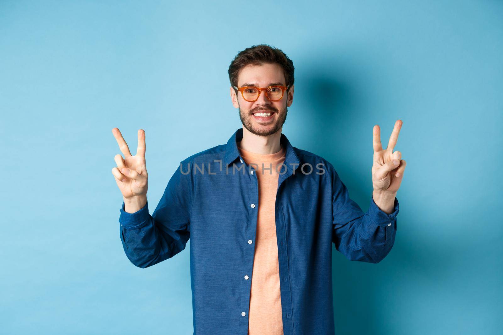 Cheerful guy posing with peace sign in new glasses, concept of eyewear shop promotion by Benzoix