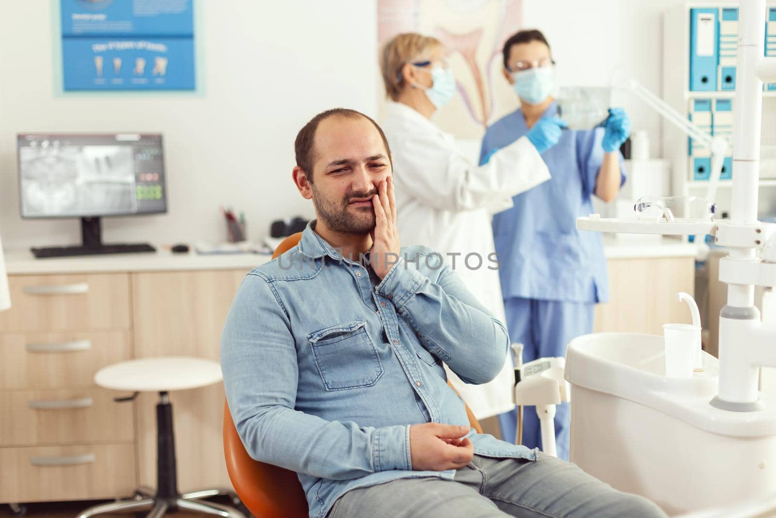Sick patient complaining about teeth pain while waiting for dentists doctors to check toothache. Senior orthodontic doctor and medical nurse examining x-ray working in hospital stomatology clinic