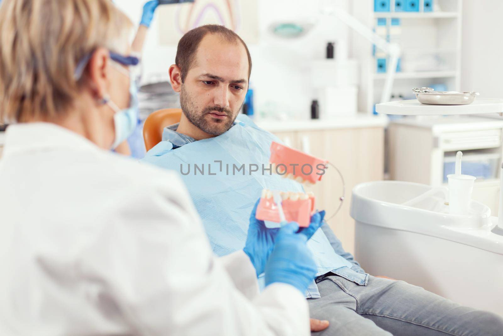 Stomatologist explaining proper dental hygiene using teeth skeleton during by DCStudio