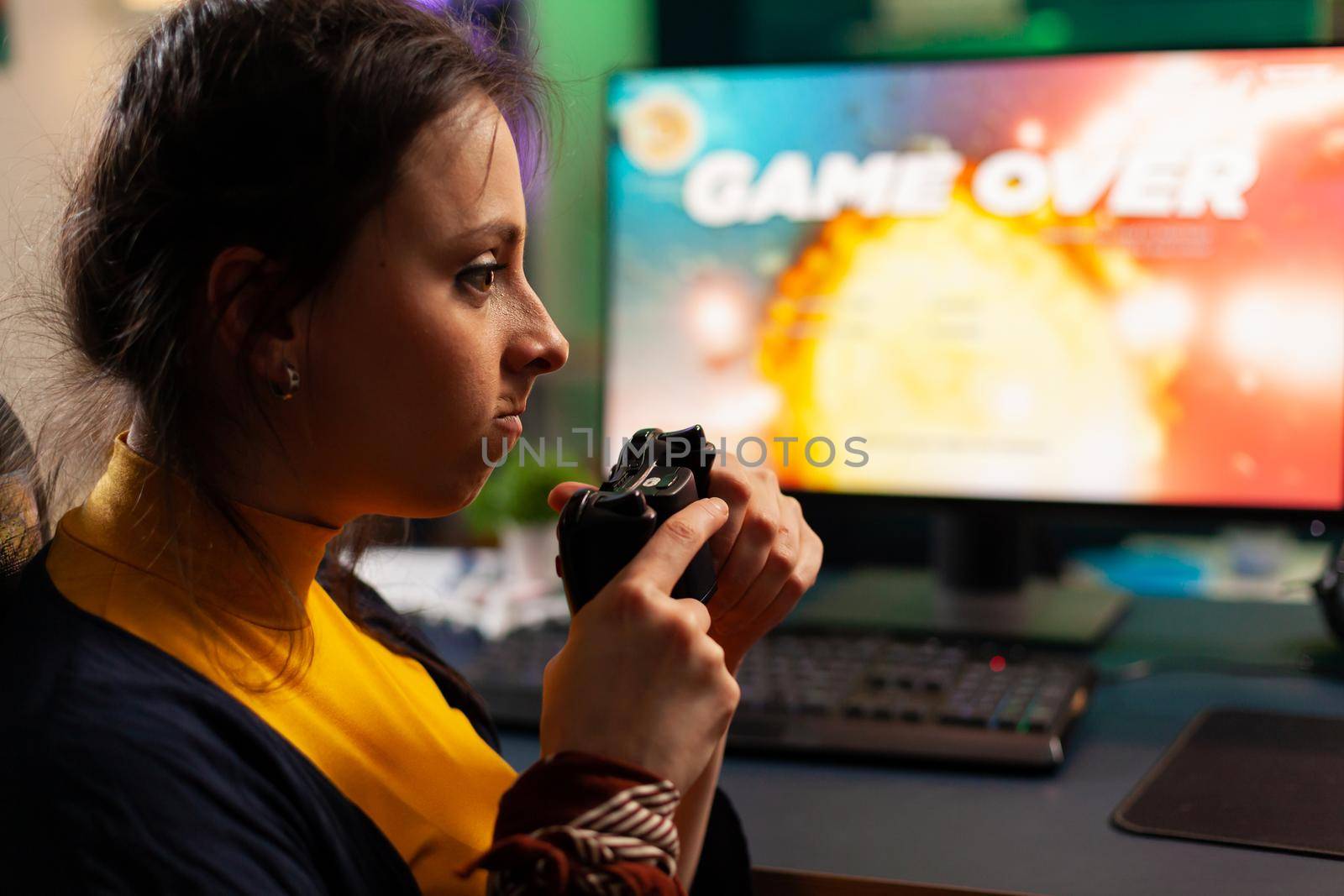 Pro player sitting on gaming chair at desk and losing space shooter video games using console. Woman streaming online videogames for esport tournament in room with neon lights