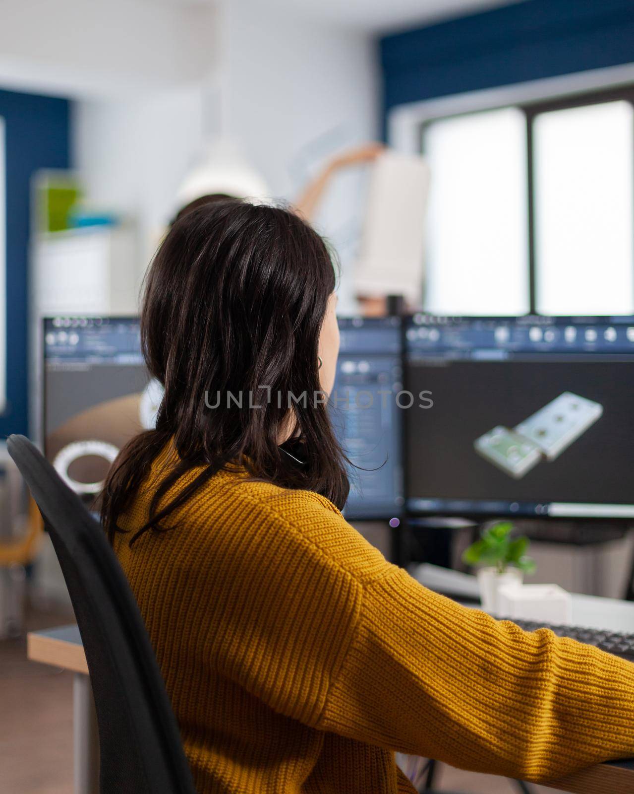 Young woman industrial engineer working at pc with two monitors by DCStudio