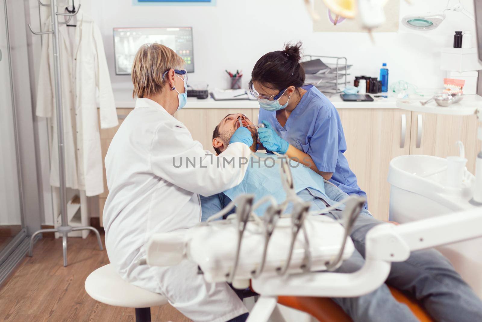 Senior woman dentist analyzing teeth examining sick patient by DCStudio