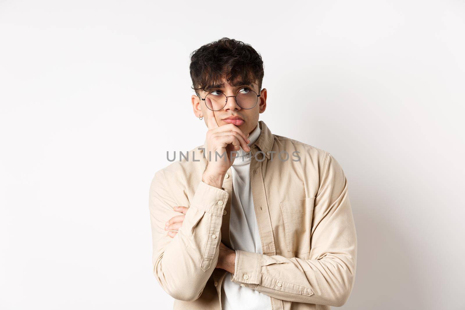 Sad and lonely young man looking at empty space with distressed face, standing thoughtful on white background.