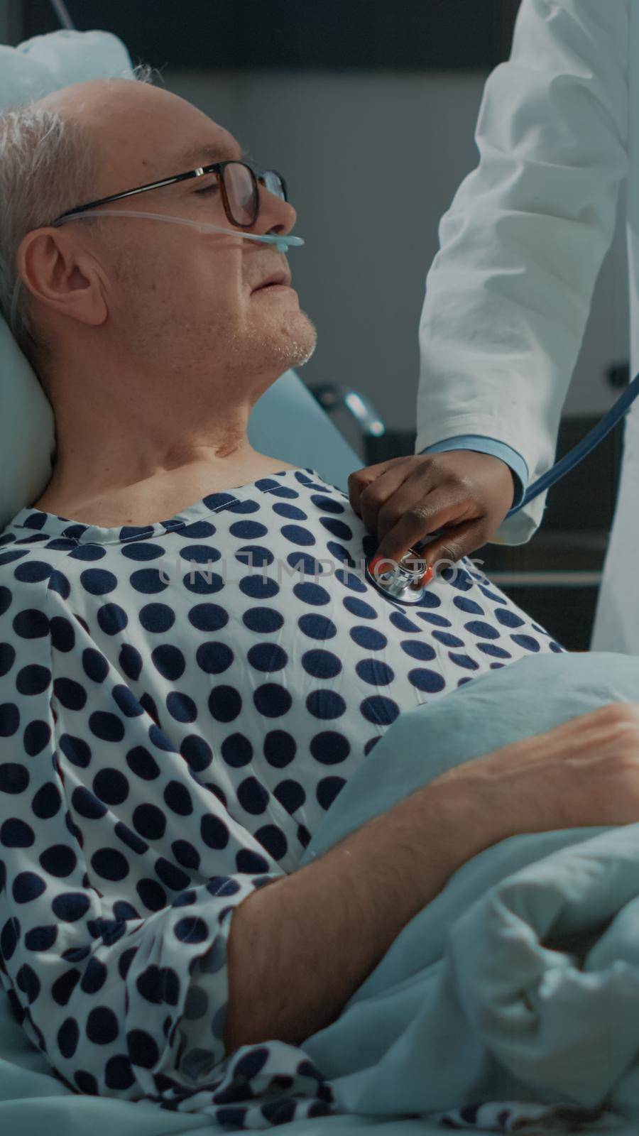 Sick patient getting consultation from african american doctor using stethoscope in hospital ward at medical recovery clinic. Nurse checking health symptoms and treatment progress