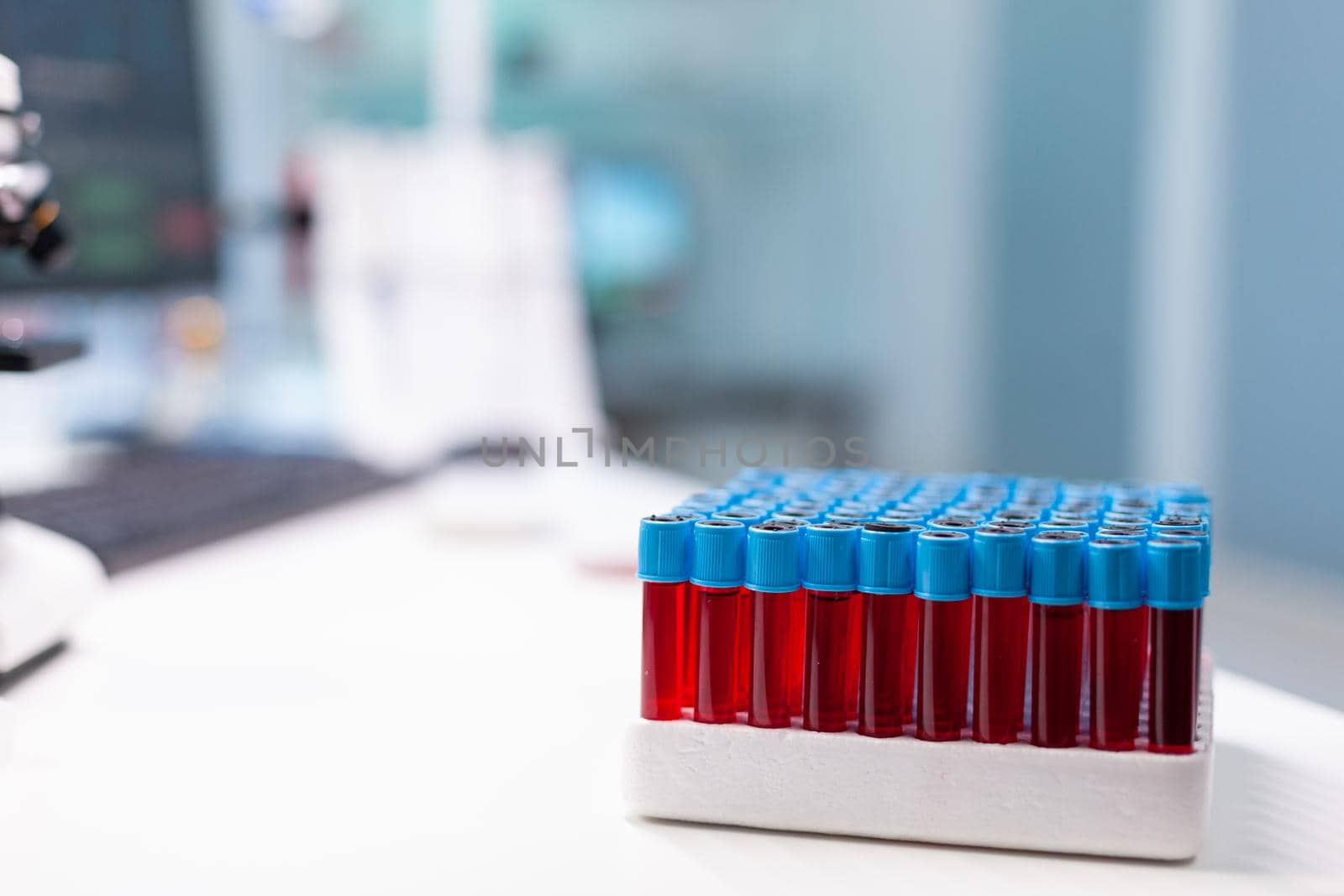 Medical vacutainer with blood sample standing on table during pharmaceutical examination in microbiology hospital laboratory. Liquid glass container ready for biological experiment