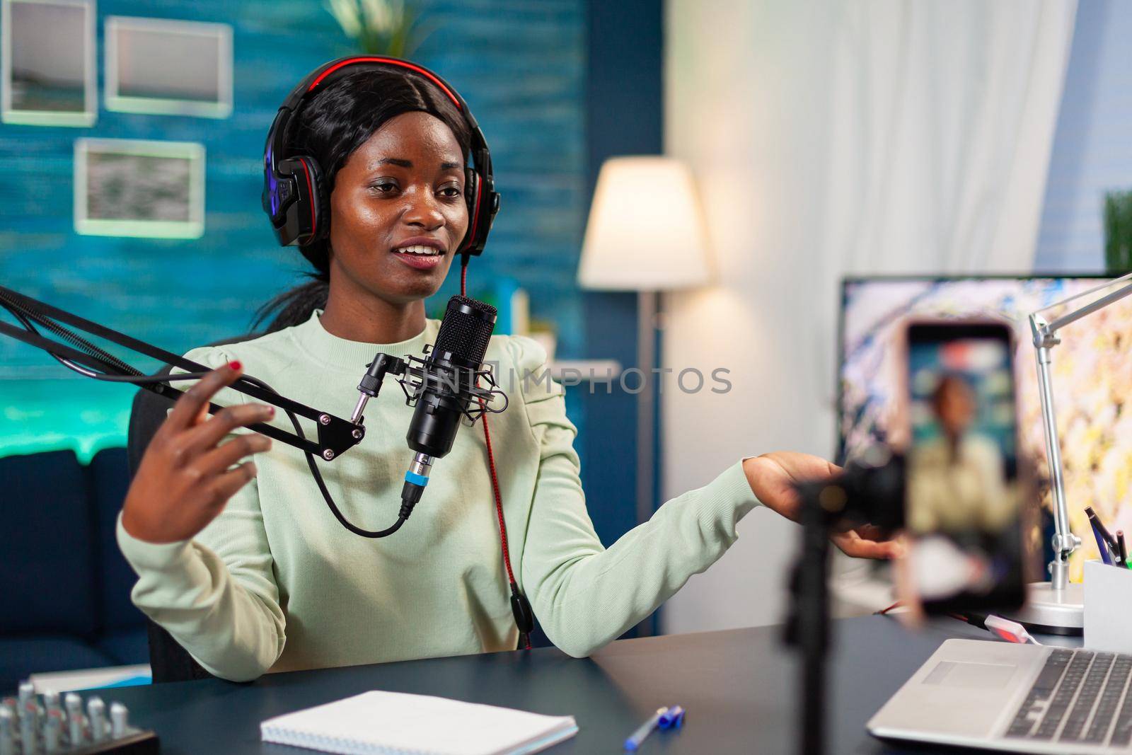 Influencer making online internet content for web subscribers in home podcast studio. Speaking during livestreaming, blogger discussing in podcast wearing headphones.