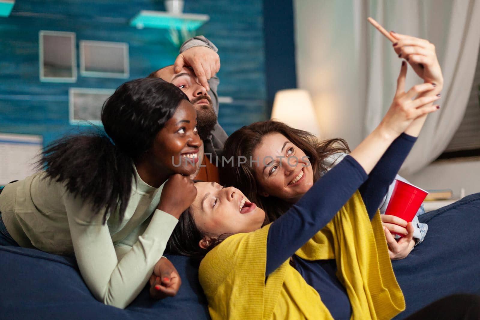 Cheerful diverse group of friends taking photos while having fun by DCStudio