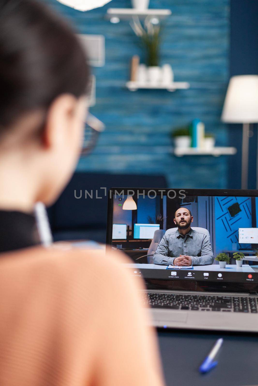 Caucasian female chatting with her math teacher during university videocall conference using laptop cumputer. Student working at communication lesson while sitting at desk in living room