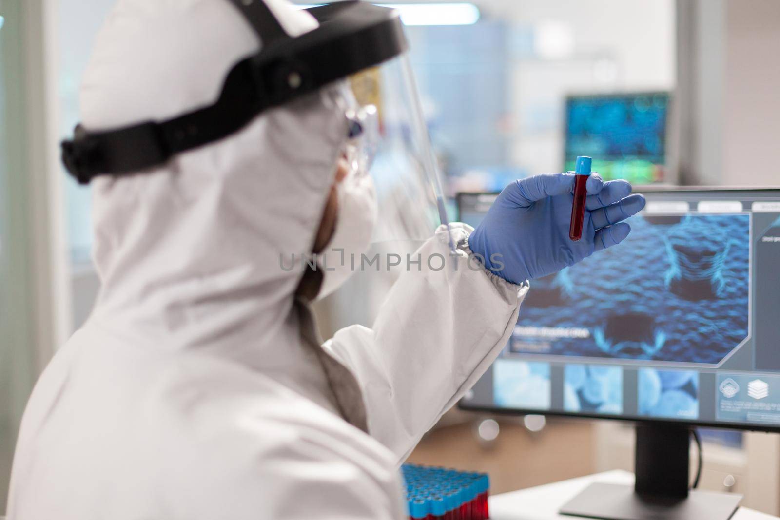 Scientist analyzing blood sample in vaccutainer dressed in ppe suit. Medical team examining vaccine evolution in medical lab using high tech and chemistry tools for scientific research