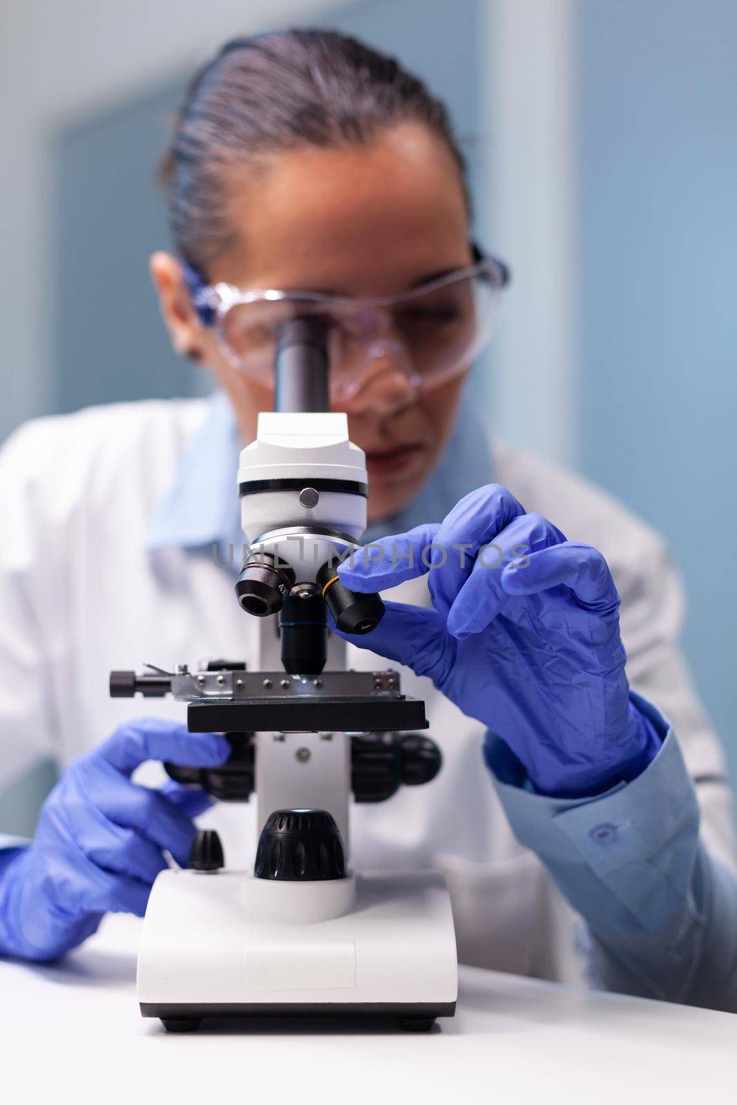 Scientist woman doctor analyzing coronavirus test results using medical microscope discovering pharmaceutical vaccine. Chemist researcher working in biochemistry pharmacology hospital laboratory