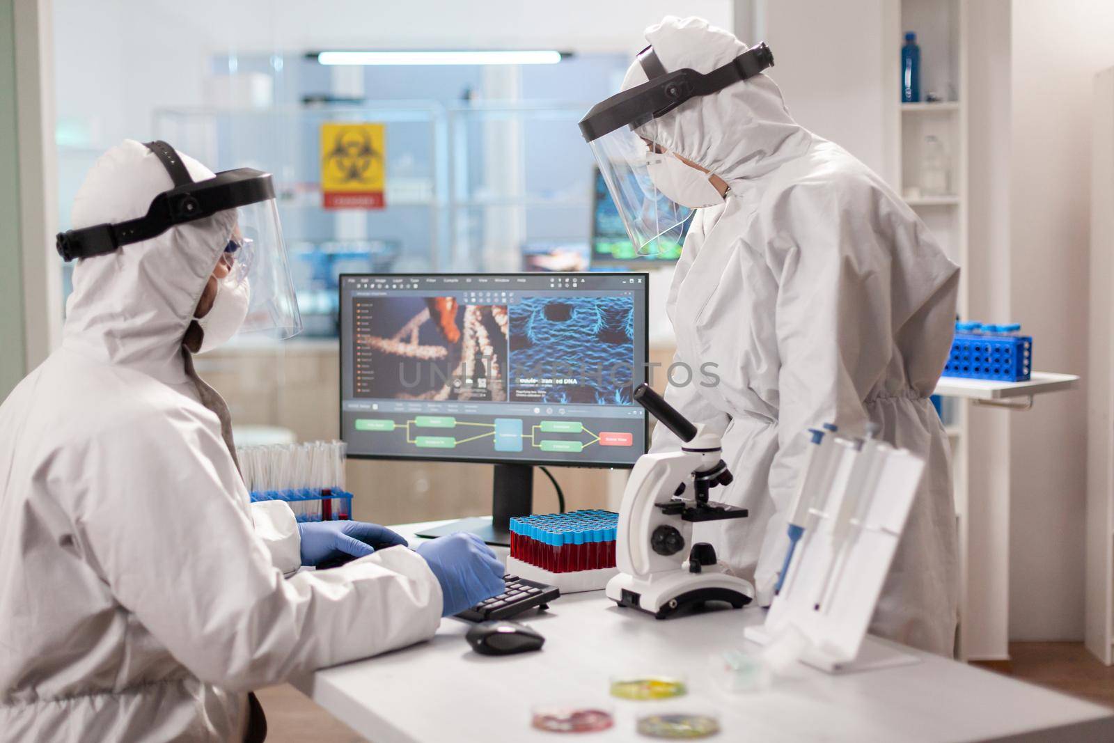 Scientists in protection suits analysing dna sample infected with virus by DCStudio