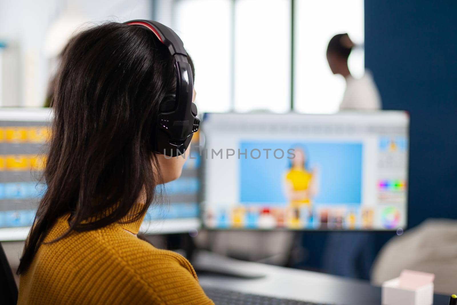 Graphic editor retouching photos of a client on performance PC with two displays setup. Woman retoucher working in photo editing software app sitting in creative agency office holding stylus pen