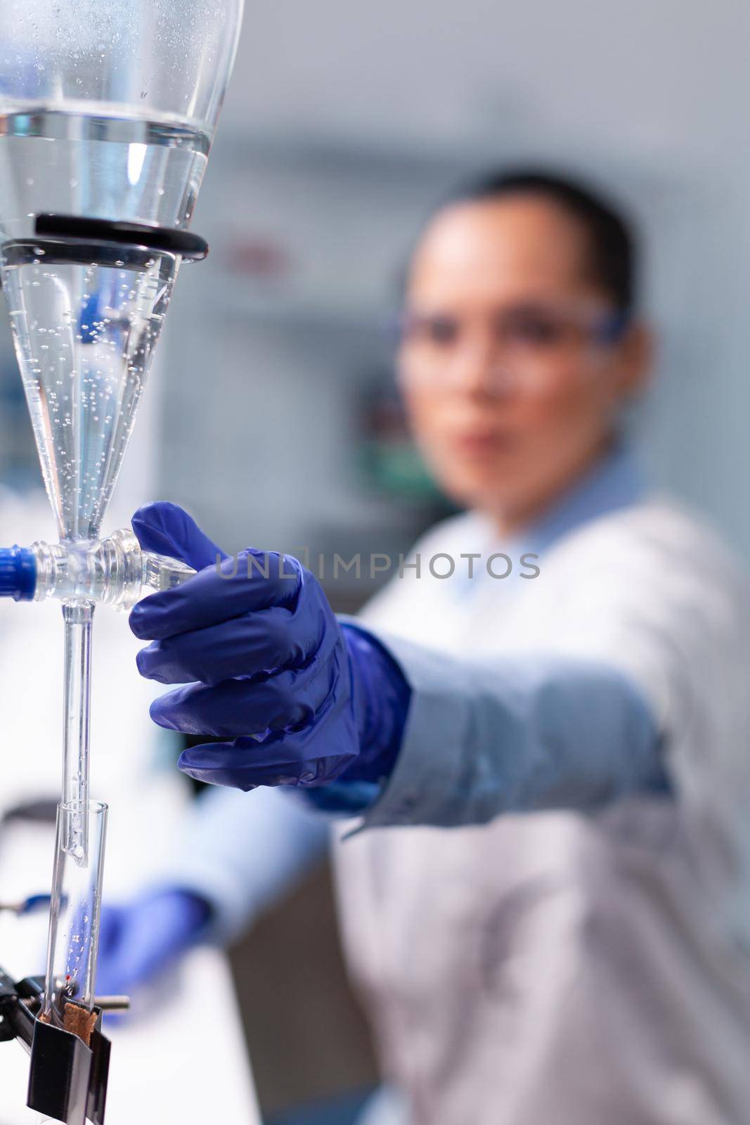 Specialist chemist woman working at biochemistry experiment using professional biology tools examining scientific chemistry research. Microbiologist doctor standing in hospital laboratory