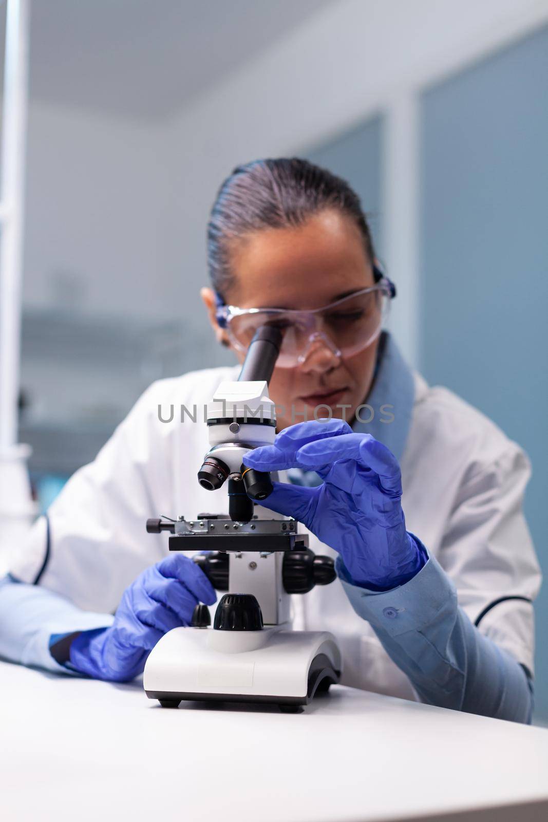 Specialist pharmacist examining bacteriology infection lab test using medical microscope working in pharmacology hospital laboratory. Scientist microbiologist analyzing microbiology expertise