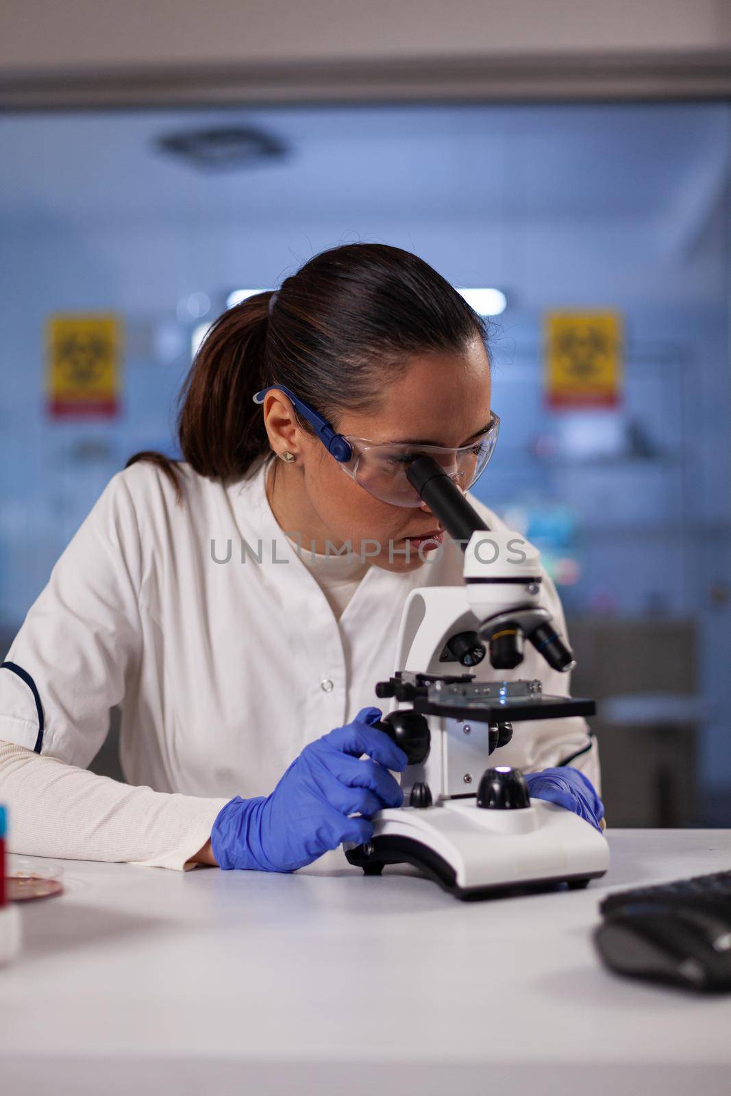 Medicine researcher woman working with microscope in chemical laboratory at medical clinic. Professional analysis worker using biotechnology equipment for discovery treatment development