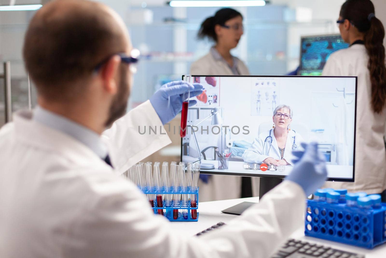 Medical expert having a conversation about virus treatment showing sample of blood during online video call. Scientist examining vaccine evolution using high tech researching treatment, health innovation, staff colaboration.