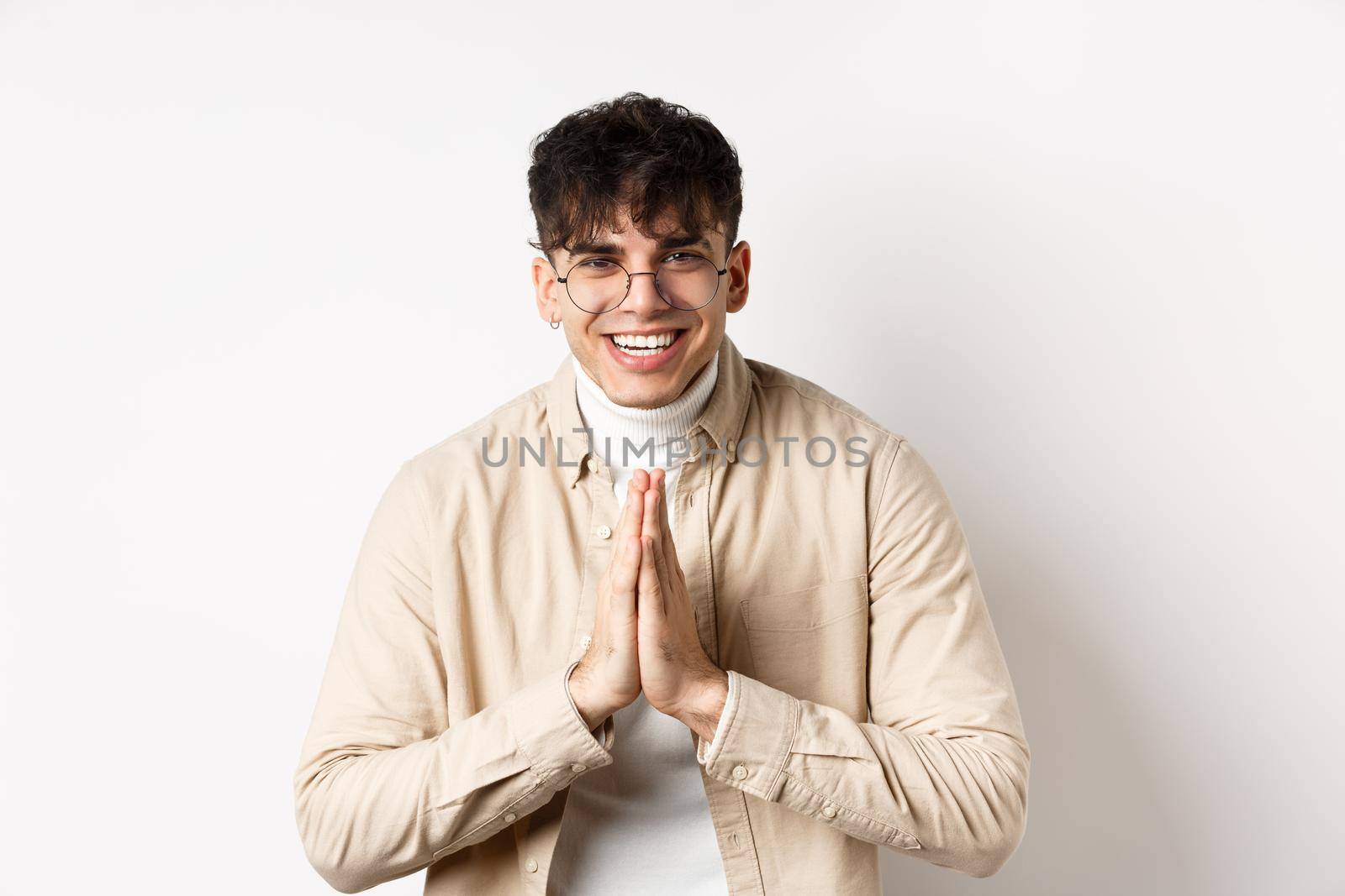 Handsome caucasian man say thank you, bowing with namaste gesture, looking grateful and smiling at camera, standing on white background.