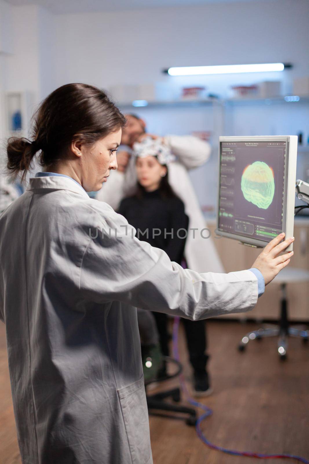 Neurology scientist examining brain nervous system scan on on monitor, machine with sensors attached to patient in laboratory. Medicine lab with modern digital machine.