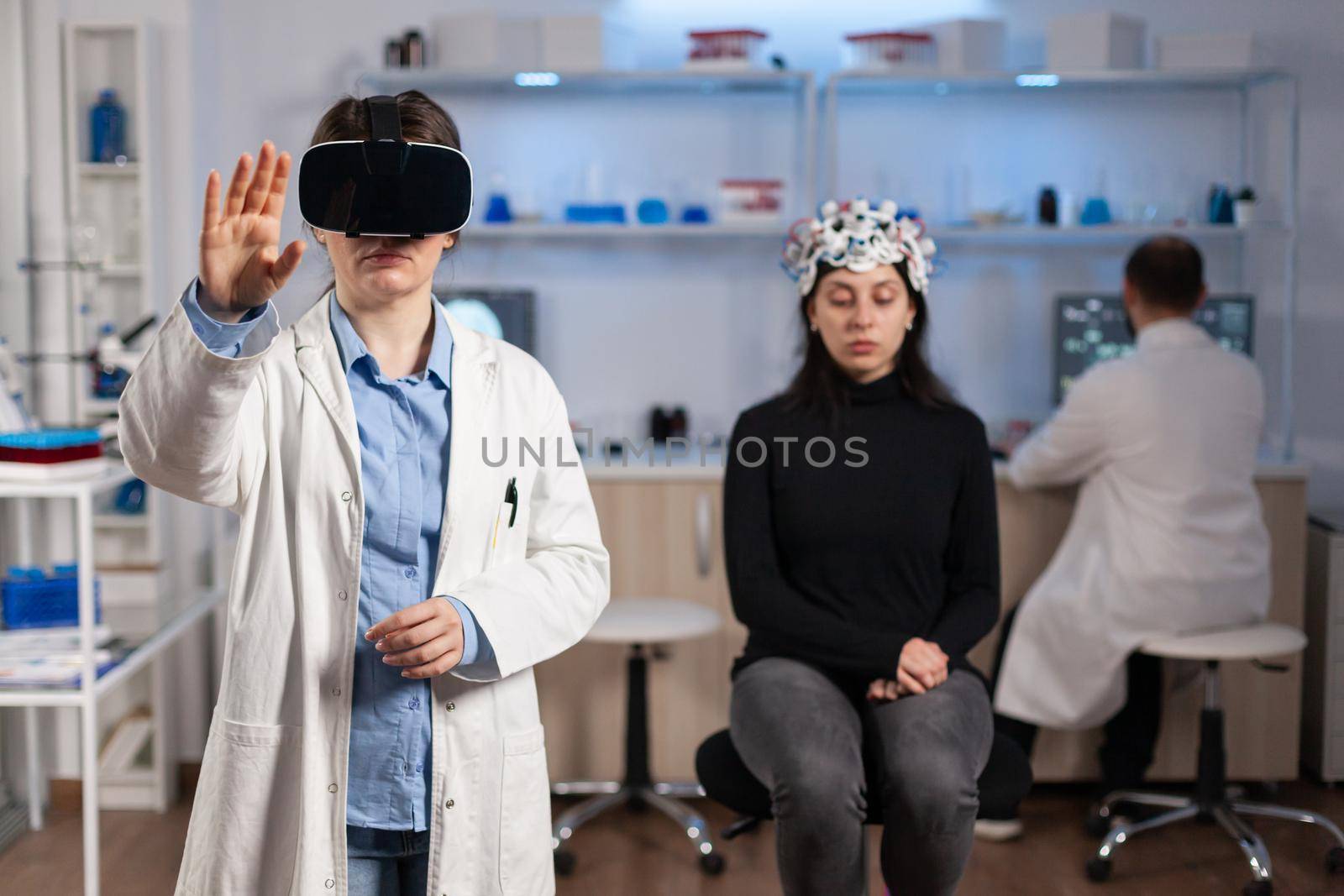 Professional researcher wearing virtual reality glasses using medical inovation in lab analysing brain scan of patient. Team of neurological doctors working with equipment high tech simulator device.