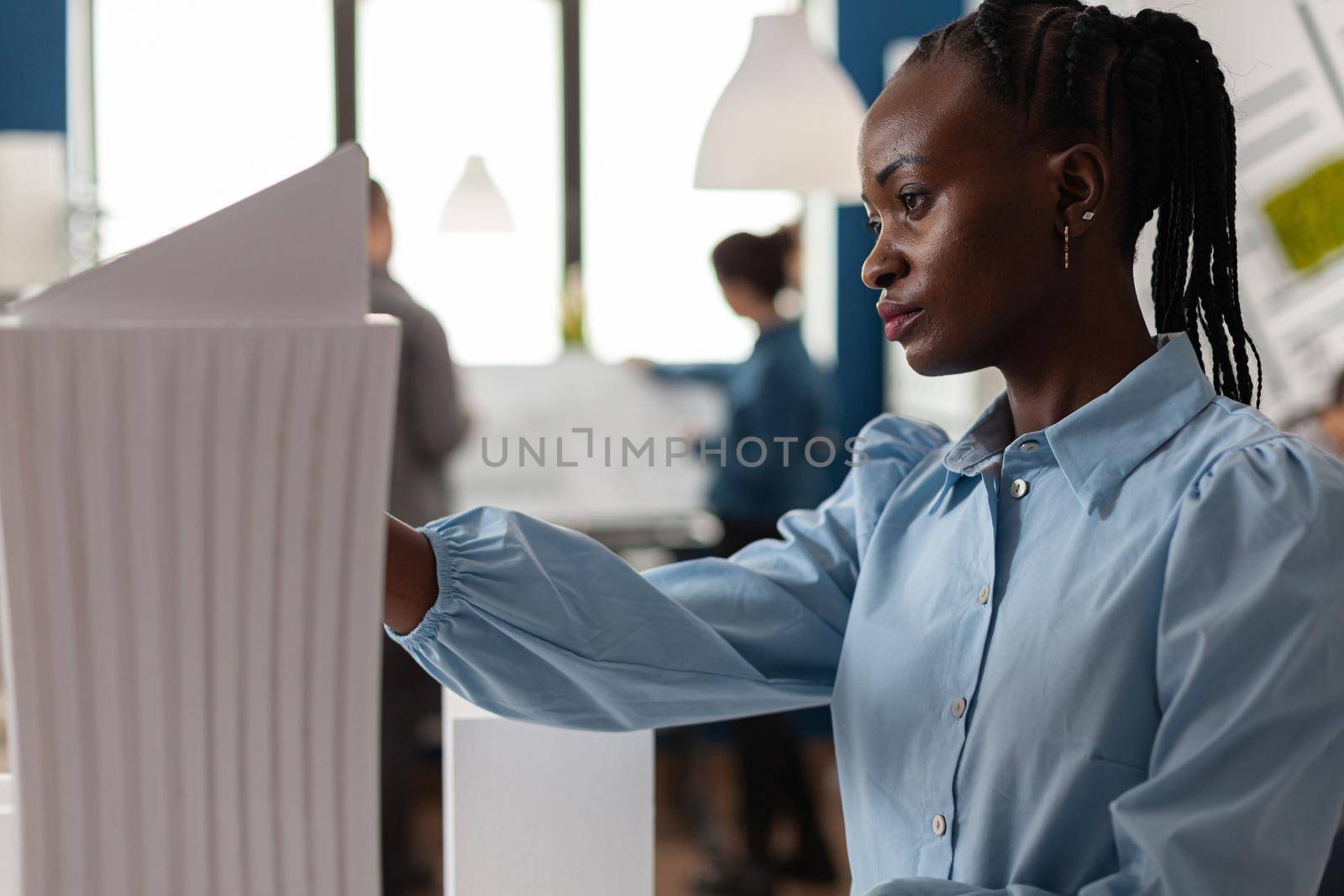 African american architect constructor at office working on building model plan design maquette. Afro woman looking at modern layout of construction for development project