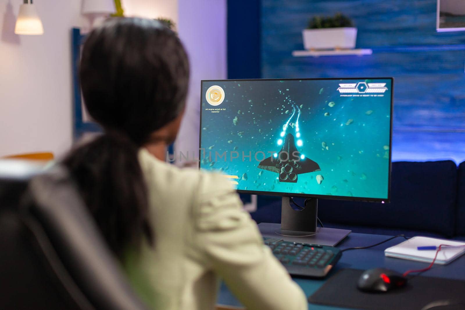 Expert woman gamer playing space shooter video game on powerful pc. Competitive cyber player woman performing videogame tournament use professional joystick.