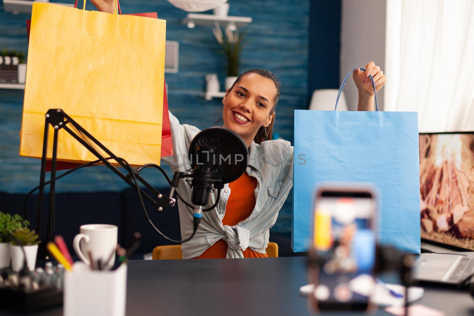 Podcast from social media vlogger with big bags gifts in home studio using professional microphone. Creative content creator influencer recording online giveaway talk show for subscribers audience