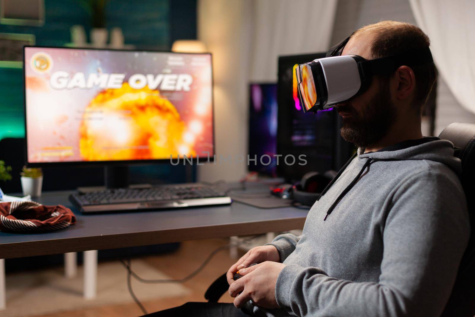 Defeated gamer man losing video game tournament playing with virtual reality headset. Competitive player using joystick for online competition late at night in gaming room