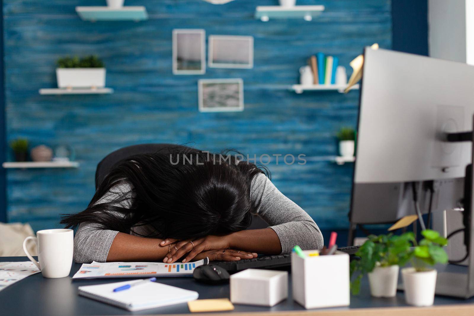 Disappointed exhausted black student sleeping on desk table in living room overworking remote from home at deadline project. Workaholic overworked african american woman searching business course