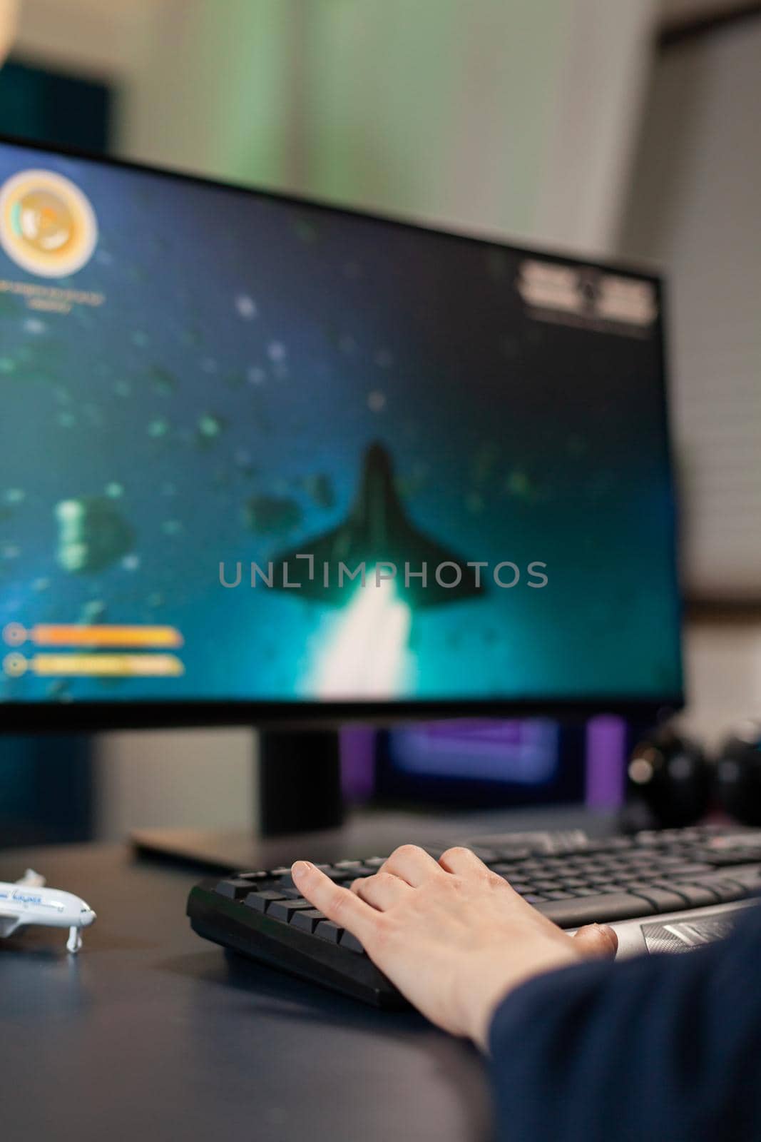 Closeup of Hand of player on professional keyboard with RGB during space shooter tournament. Pro gamer playing on gaming desk in home studio streaming online videogames