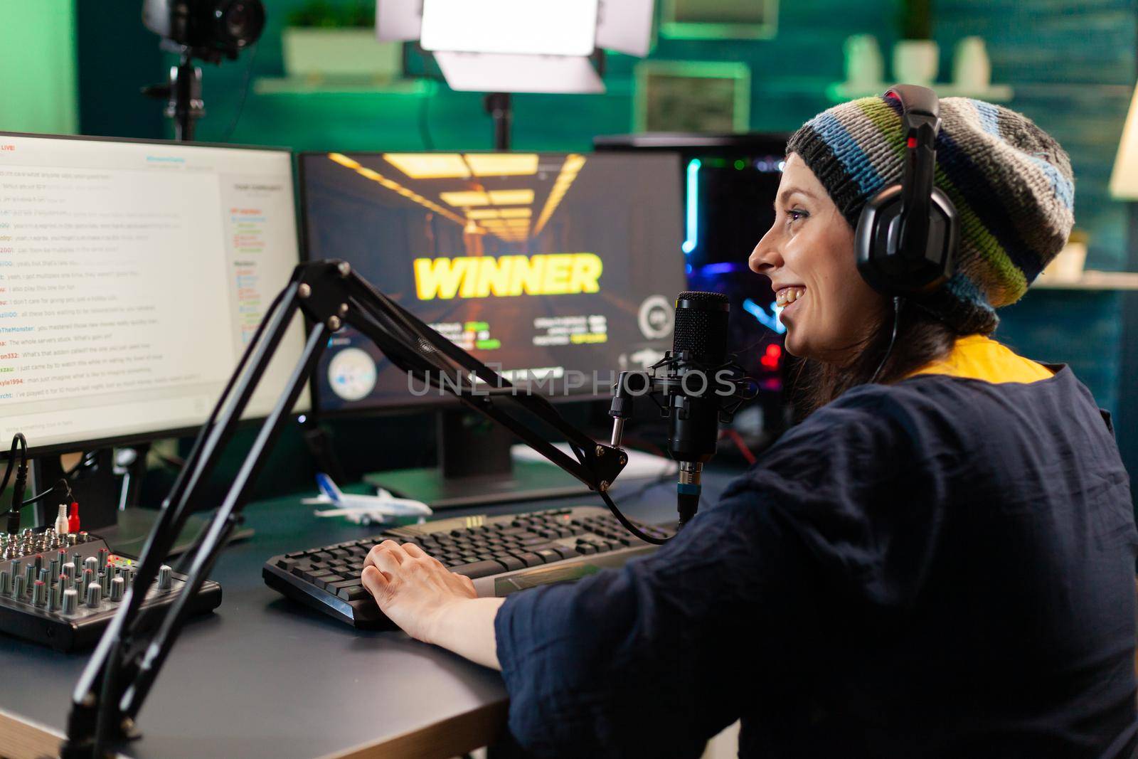 Back view of upseted streamer playing game competition using professional setup with streaming chat open. Gamer sitting on gaming chair using wireless controller and professional headphone