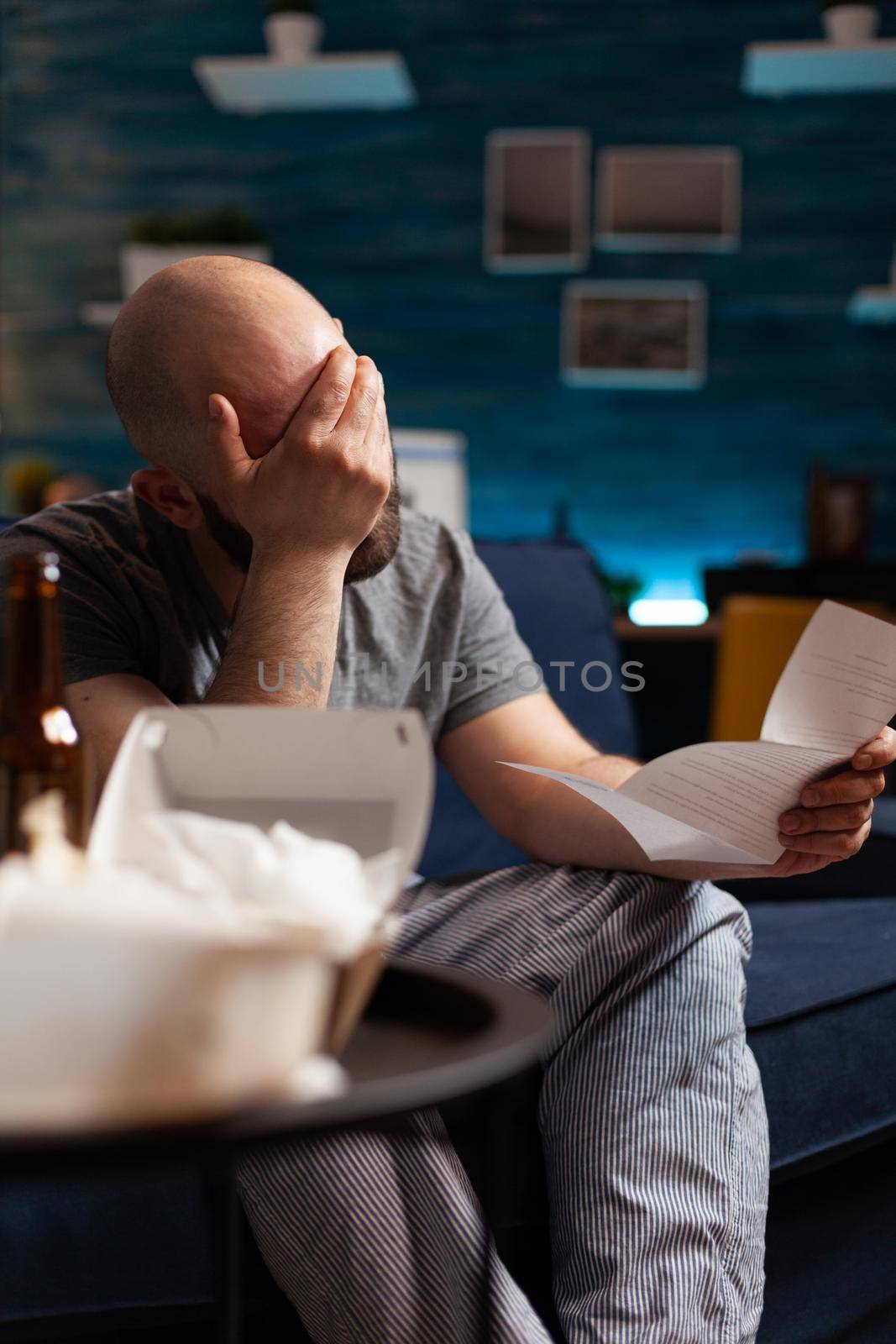 Desperate, depressed, frustrated man reading renter paper letter with banking bills crying while looking at eviction notice. Shocked unhappy male having problems bankruptcy, unexpected bad news