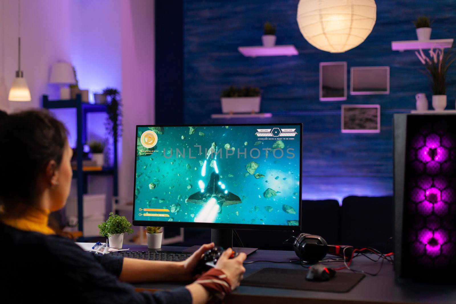 Concentrated player sitting on gaming desk late at night by DCStudio