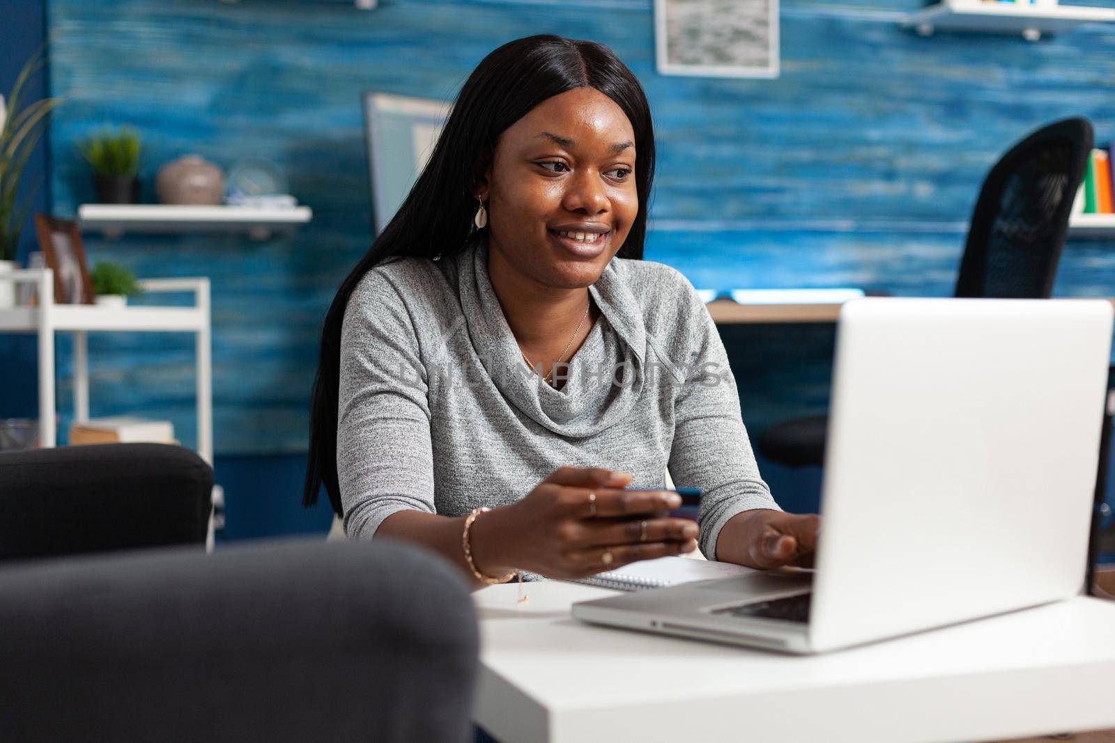 African american student making online sale shopping holding economy credit card in hands by DCStudio