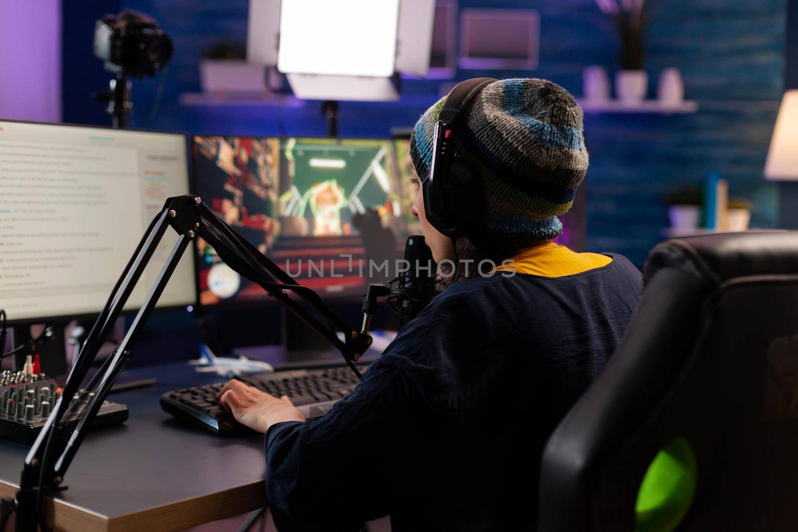 Professional streamer playing shooter games wearing headphones and talking into microphone via streaming chat. Gamer making online videogames with new graphics on powerful computer