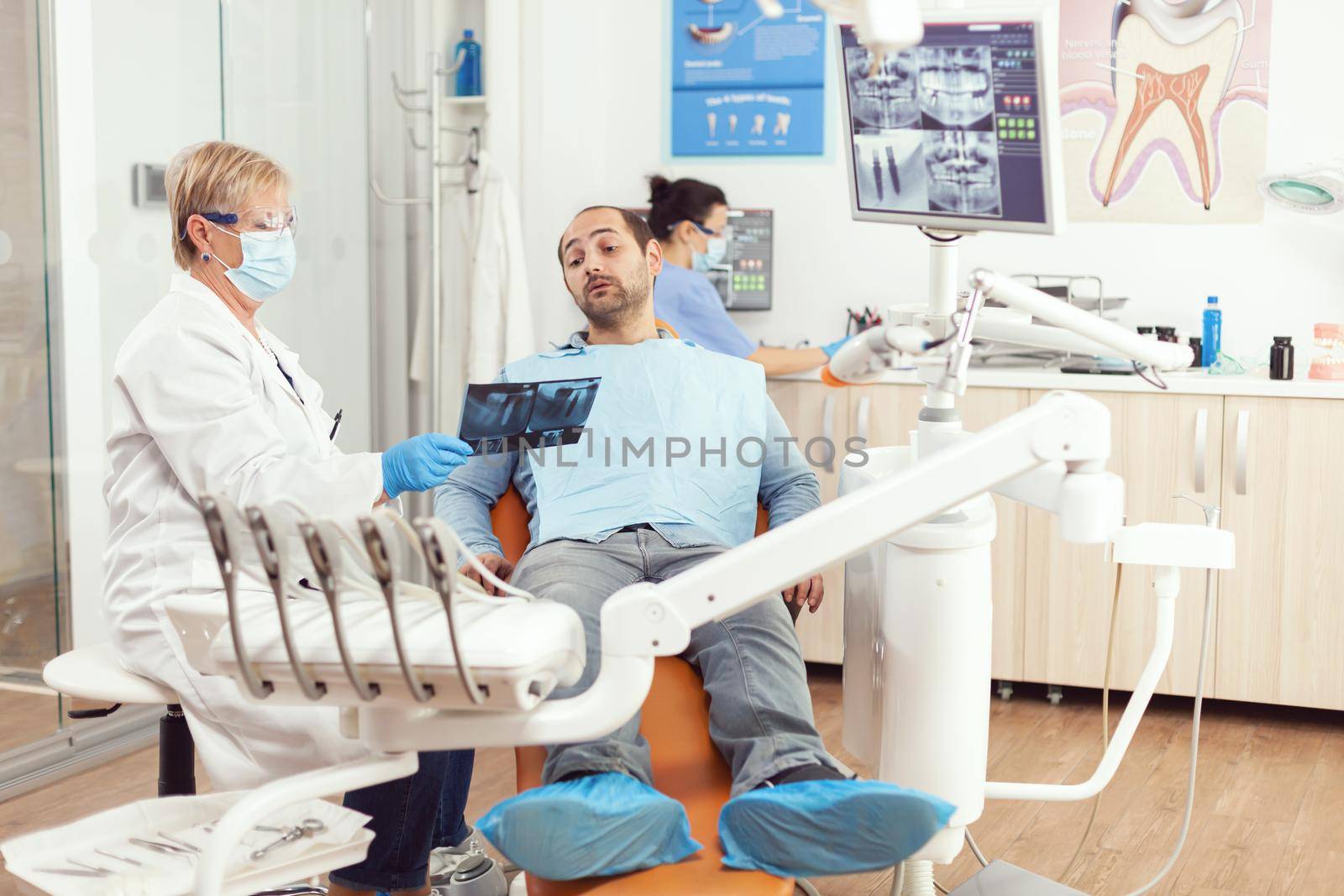 Senior woman dentist treating sick man patient in modern stomatological dentistry office by DCStudio