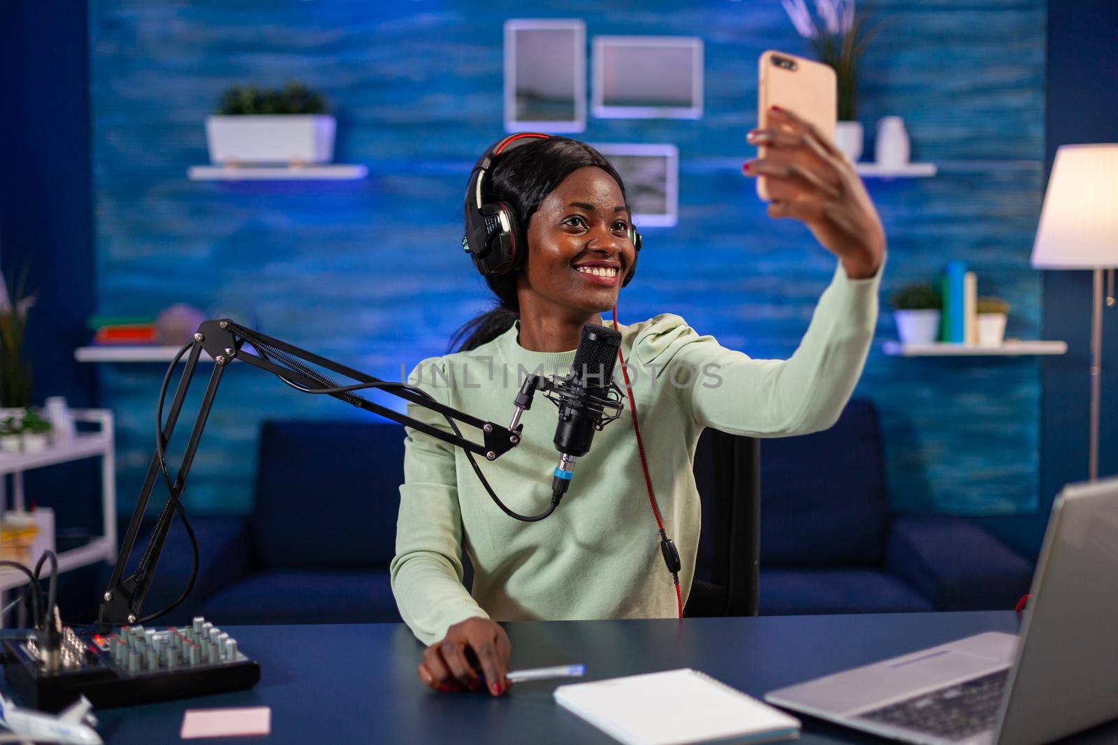 African influencer talking a selfie for listener while recording vlog. On-air online production internet podcast show host streaming live content, recording digital social media.