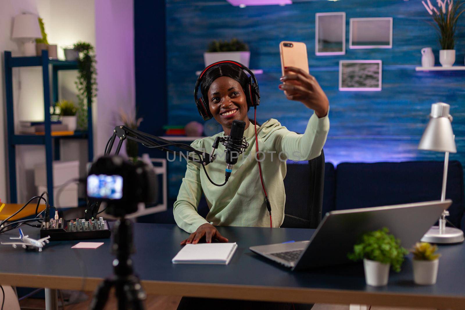 African woman using smartphone to take photo in entertainment business recording episode. On-air online production internet podcast show host streaming live content, recording digital social media.