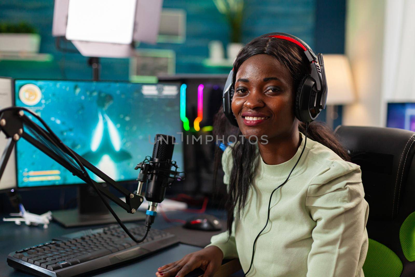 Portrait of african professional e streamer player looking at camera. Streaming viral video games for fun using headphones and keyboard for online championship.