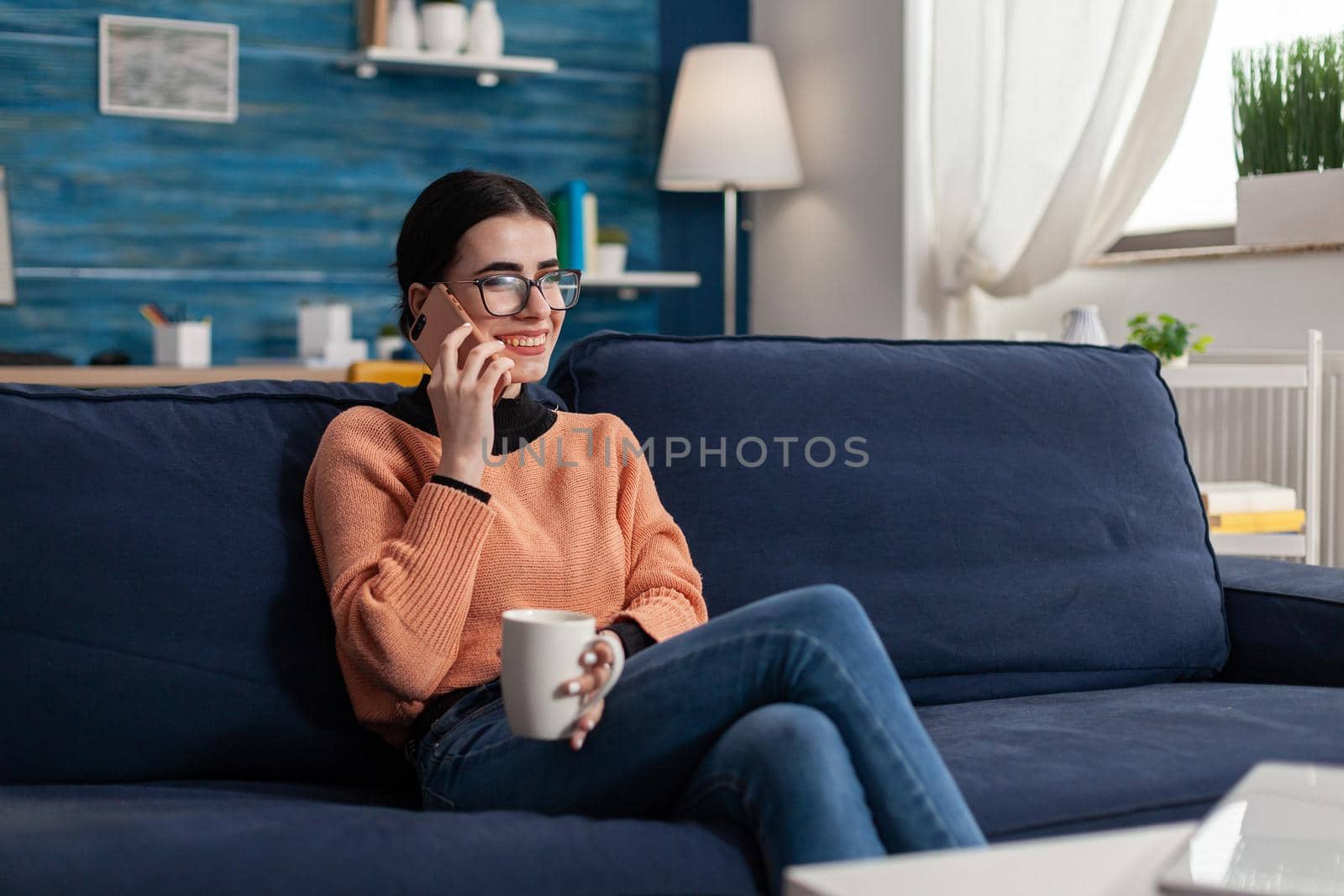 Student smiling while talking on phone holding cup of coffee by DCStudio