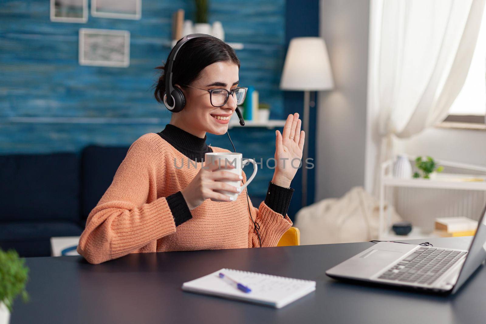 Student wearing headphone while waving her college treacher by DCStudio