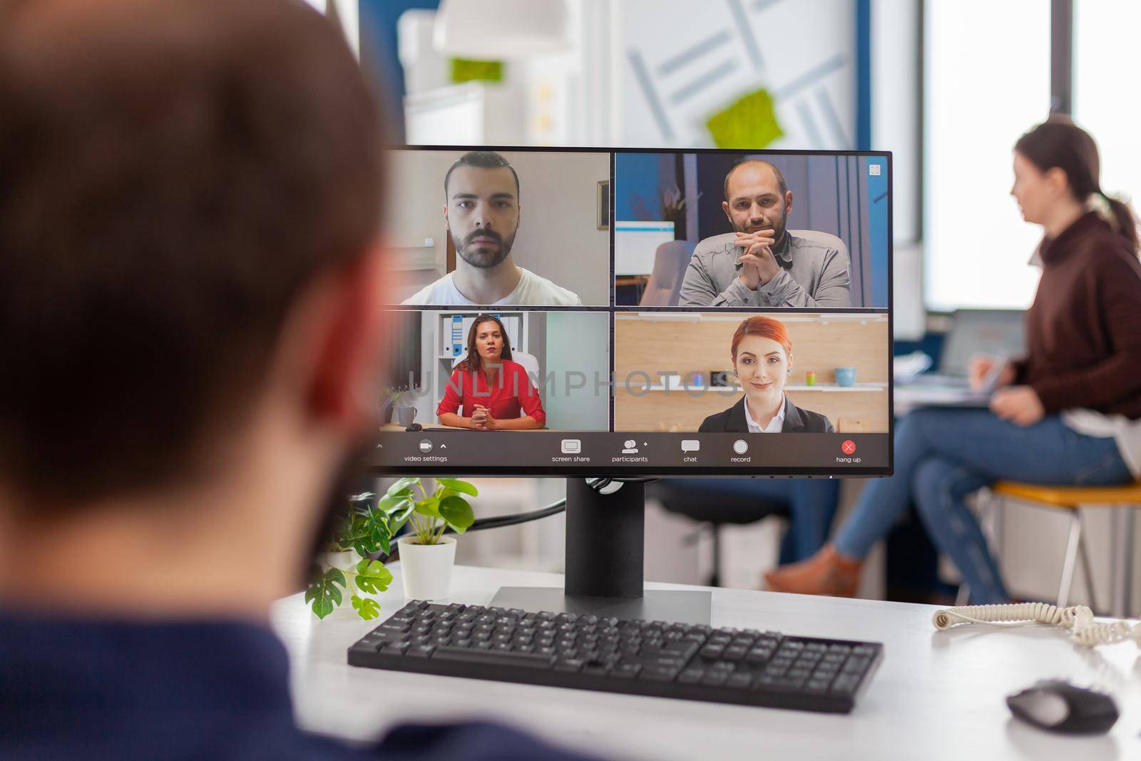 Paralysed handicapped businessman sitting immobilized in wheelchair having videomeeting discussing online with remotely colleagues in business office. Invalid employee working in financial company.