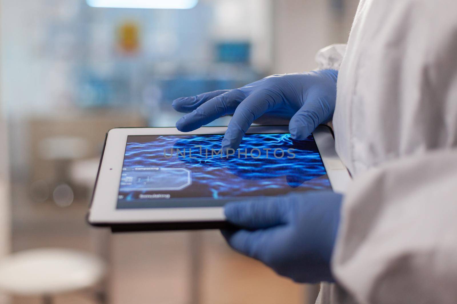 Close up of chemist in ppe suit using tablet pc to check virus vaccine. Scientist examining virus evolution using high tech technology researching vaccine development against covid19.