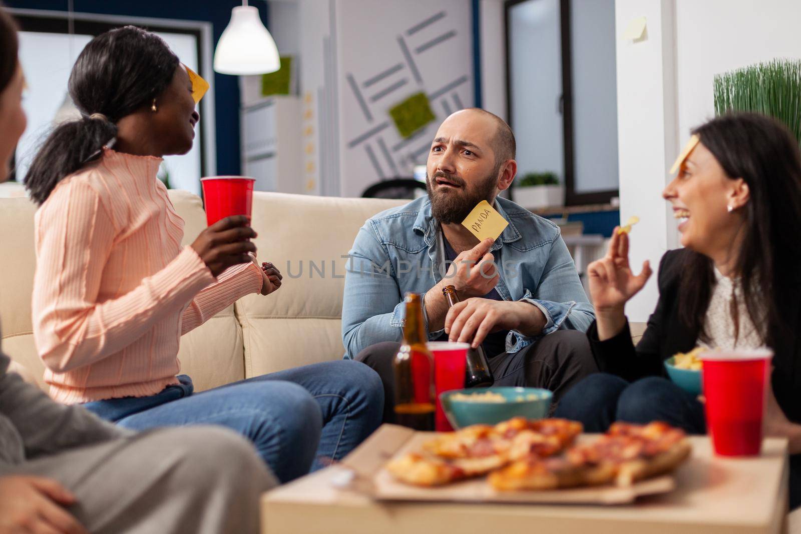 DIverse team of coworkers playing charades after work by DCStudio